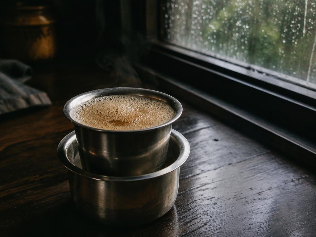 South Indian filter coffee poured between a steel davara and tumbler